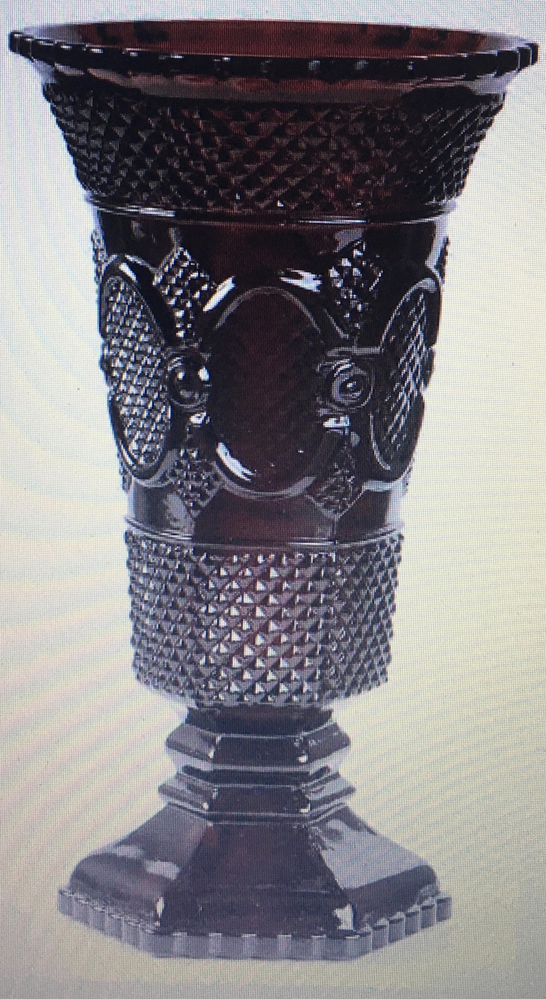 May include: A dark purple glass vase with a diamond pattern and intricate designs. The vase has a wide mouth and a square base.