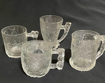 May include: Four clear glass mugs with different designs. Each mug has a unique handle and features the text "Huston's" on the side.