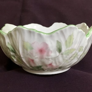 Puede incluir: Un tazón de porcelana blanca con un borde verde y un diseño floral con flores rosas y hojas verdes.