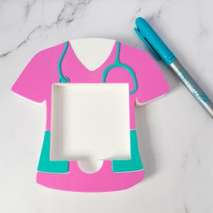 Healthcare Office Accessory Nurse Sticky Holder Medical Note Organizer Professional Desk Supply Hospital Workspace Organization Stethoscope Detail Design Scrub Top Shape Pink Teal Colors PLA Material Construction Practical Memo Storage
