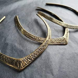 May include: Three gold-colored metal collars with intricate embossed designs. The collars are stacked on top of each other.