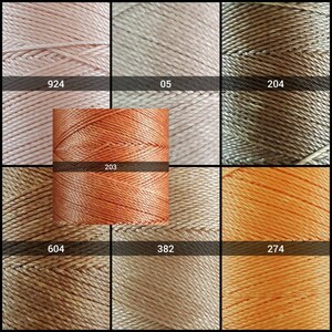 May include: Nine spools of thread in various shades of peach, orange, and brown. The spools are labeled with numbers: 924, 05, 204, 203, 604, 382, and 274.