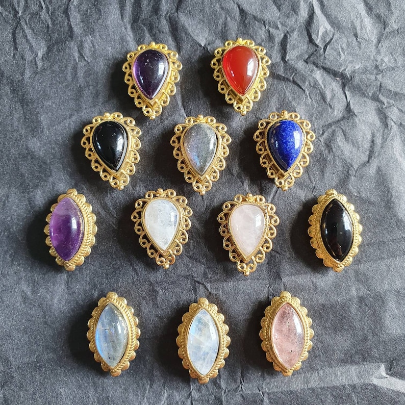 May include: Assortment of 12 gold-tone pendant charms with various gemstone colors, including amethyst, red, black, blue, and white. Each charm features a teardrop-shaped gemstone set in a delicate filigree design.