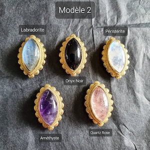 May include: Six different gemstone cabochons set in gold-toned bezels. The stones are labradorite, onyx, moonstone, amethyst, rose quartz, and peristerite.  The stones are all oval shaped and have a smooth, polished finish.  The bezels are ornate and have a detailed design.  The stones are arranged in a row on a dark gray background.  The text "Mod&egrave;le 2" is at the top of the image.