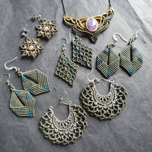 May include: A collection of handmade jewelry featuring a variety of styles, including earrings and a necklace. The earrings are made with green and blue macrame, and the necklace features a gold chain with a purple gemstone pendant.