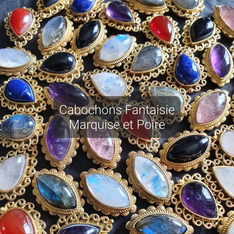 May include: A collection of gemstone cabochons in various colors and shapes, including marquise and pear cuts, set in gold-toned metal settings. The stones include moonstone, amethyst, labradorite, and carnelian.