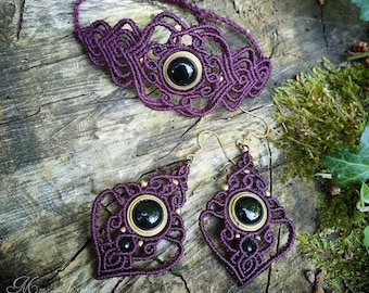 May include: A set of purple macrame jewelry with black gemstone accents. The set includes a choker necklace and a pair of earrings.