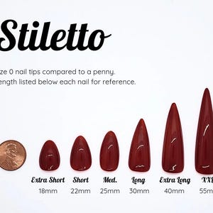 Puede incluir: Un conjunto de seis puntas de u&ntilde;a stiletto de color rojo oscuro en longitudes variables de 18mm a 55mm, etiquetadas Extra Short, Short, Med., Long, Extra Long y XXL. Se muestra un centavo de cobre para escala. El texto dice Stiletto.
