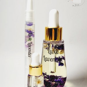 May include: Three glass bottles with gold caps and labels that say "Luxe Lavender". The bottles contain a clear liquid with dried flowers inside.