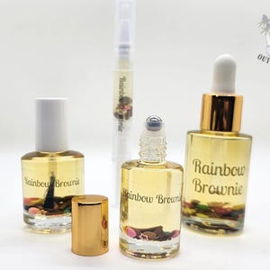 May include: A collection of nail care products, including a nail polish bottle, a rollerball bottle, a dropper bottle, and a pen-style cuticle oil applicator. The bottles are filled with a clear liquid and decorative elements, with the words "Rainbow Brownie" on them.