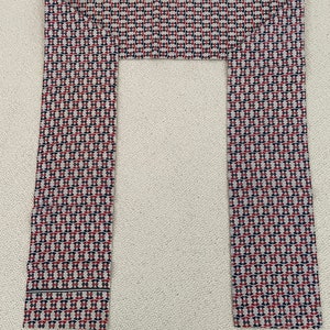 May include: A pair of fabric strips with a geometric pattern in shades of red, blue, and white. The strips are folded to form a frame.