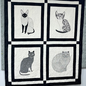 May include: A black and white quilt with four squares featuring different black and white cat illustrations. Each square has a white background with a black border and a black and white swirl pattern.