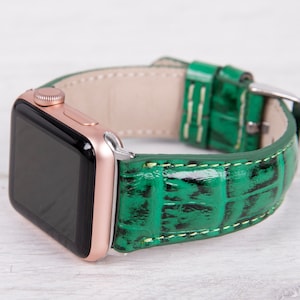 May include: A rose gold Apple Watch with a green crocodile-embossed leather band.