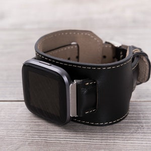 May include: A black leather watch band with a silver buckle and a black square watch face.