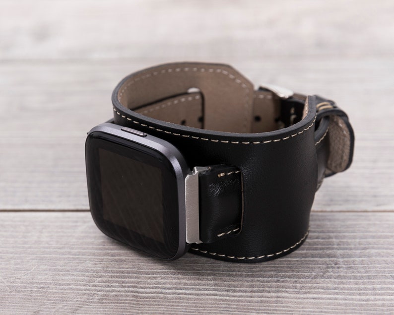 May include: A black leather watch band with a silver buckle and a black square watch face.