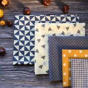 Könnte beinhalten: Satz mit sechs wiederverwendbaren Lebensmittelverpackungen mit verschiedenen Mustern. Die Verpackungen haben ein geometrisches Muster, ein Bienenmuster, ein Punkte-Muster, ein einfarbiges gelbes Muster und ein Karomuster.