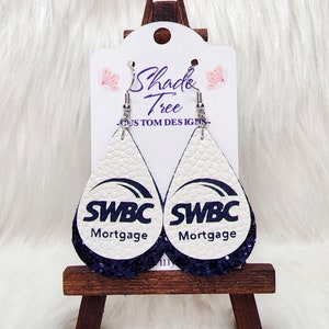 May include: A pair of white teardrop-shaped earrings with a purple glitter finish. The earrings feature the logo "SWBC Mortgage" in black text.