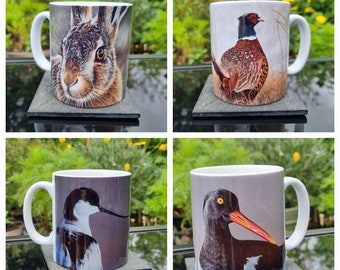 Può includere: Quattro tazze in ceramica bianca con illustrazioni di fauna selvatica. Una tazza presenta una lepre, un'altra un fagiano, una terza un uccello con un lungo becco e l'ultima un'ostrica. Ogni tazza è su un sottobicchiere di ardesia.