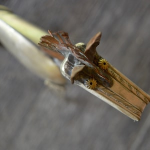 May include: A silver and copper metal sculpture of a horse's head with gold accents. The horse's mane is made of copper wire and the eyes are made of gold.