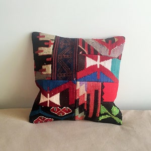 Peut inclure: Un coussin patchwork coloré avec un motif géométrique dans des tons de rouge, bleu, vert, noir et blanc.