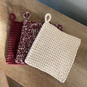 May include: Three crocheted pot holders. One is cream colored, and the other two are burgundy with white accents.