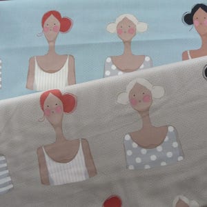 Peut inclure: Deux rouleaux de tissu avec un motif répété de femmes stylisées. Les femmes ont différentes coiffures et portent des débardeurs ou des chemises rayées. Le tissu est bleu clair et beige. Le texte "Todd Quilt Collection" est visible.