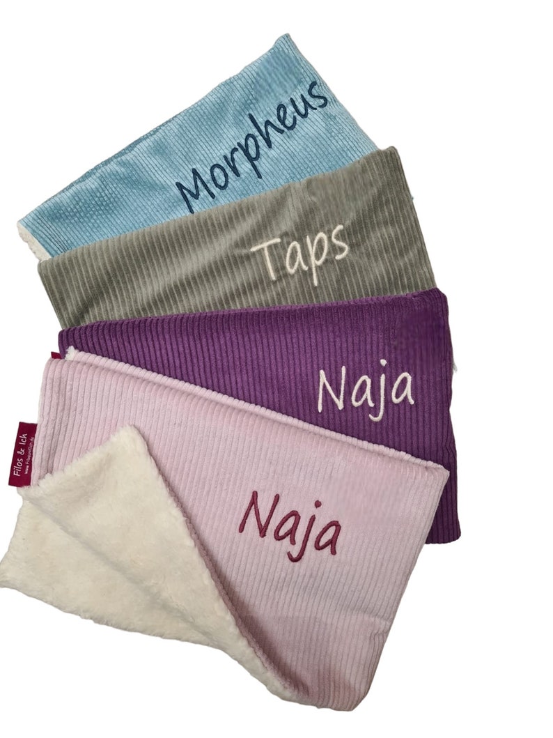 May include: Four personalized baby blankets in different colors and textures. The blankets are stacked on top of each other, with the top blanket folded in half. The blankets are made of a soft, plush material and have the names "Morpheus", "Taps", "Naja", and "Naja" embroidered on them.