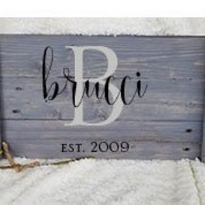 May include: A gray wooden serving tray with black metal handles. The tray is personalized with a large white letter "B" and the name "brucci" in cursive. The text "EST. 2009" is also printed on the tray.