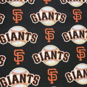 May include: Black fabric with a repeating pattern of baseballs and the San Francisco Giants logo. The word "GIANTS" is in white letters with an orange outline, and the baseballs are cream-colored.