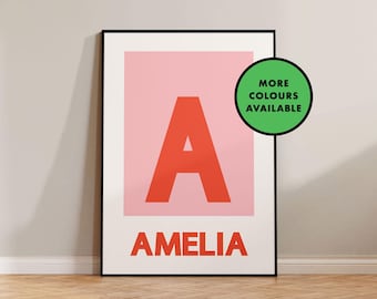 May include: A pink and white printable poster with a large red letter A and the name Amelia printed below. The poster has a green circle with the text "More Colours Available" in white.
