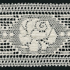 May include: A close-up of a delicate white crocheted lace trim with a floral pattern.