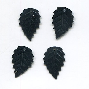 May include: Four black leaf-shaped metal embellishments with a hole at the top.