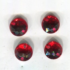 May include: Four red round rhinestones with a faceted design.