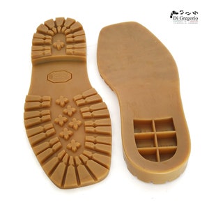 May include: A pair of brown rubber shoe soles. One sole has a textured tread pattern and the other has a grid pattern.