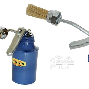 Op de afbeelding: Een blauwe oliekruik met een borstelapplicator. De kan heeft een zilveren hendel en een label met de tekst "PERFETTO". De borstel is bevestigd aan een metalen arm en is gemaakt van lichtbruine borstelharen.