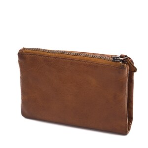 May include: A brown leather wallet with a zipper closure. The wallet is rectangular and has a slightly distressed appearance. The zipper is silver-toned, and the leather has a warm, earthy tone.