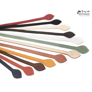 Könnte beinhalten: Ein Set aus 12 Lederriemen mit einem blattförmigen Ende. Die Riemen sind in verschiedenen Farben, darunter Schwarz, Braun, Rot, Grün und Beige.