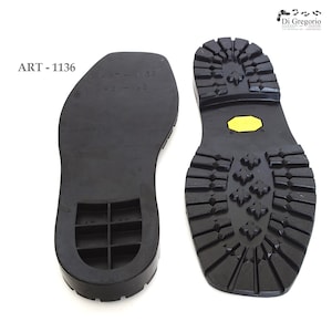 May include: Two black rubber shoe soles, one with a textured tread pattern and the other with a smooth surface and a grid pattern. The sole with the tread pattern has a yellow patch on the heel. The text "ART - 1136" is printed on the image.