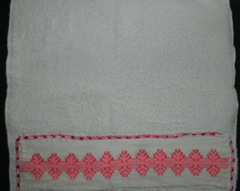 May include: White towel with a pink embroidered border. The embroidery features a repeating pattern of small pink flowers.