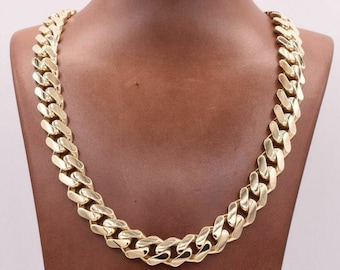 May include: A thick gold chain necklace with a curb link design. The chain is made of solid gold and has a polished finish.