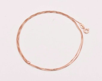 May include: A fine rose gold box chain necklace, presented against a white backdrop. The necklace's intricate design and warm colour are highlighted. The clasp is visible, indicating its ready-to-wear nature. The chain measures approximately 40 cm.