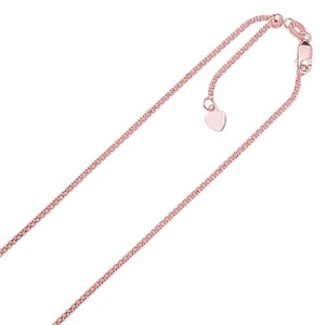 Puede incluir: Collar ajustable de oro rosa con una cadena delicada. El collar presenta un pequeño dije en forma de corazón y un cierre de mosquetón. La cadena está finamente detallada y tiene un brillo sutil.