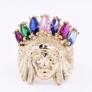 Könnte beinhalten: Ein goldener Ring mit einem Design eines indianischen Häuptlings. Die Kopfbedeckung des Häuptlings ist mit bunten Edelsteinen in Rot-, Grün-, Blau-, Lila- und Rosatönen verziert.