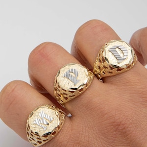 Pode incluir: Três anéis de sinete de ouro com um design de corte de diamante. Cada anel apresenta uma letra "P" em relevo no centro.