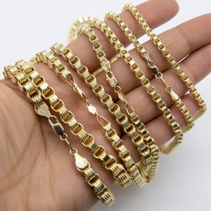 May include: A set of five gold chains with a woven design. The chains are arranged in order of size, with the largest chain at the bottom and the smallest chain at the top.