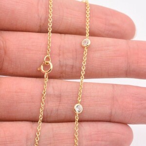 May include: A gold chain necklace with two small clear stones.