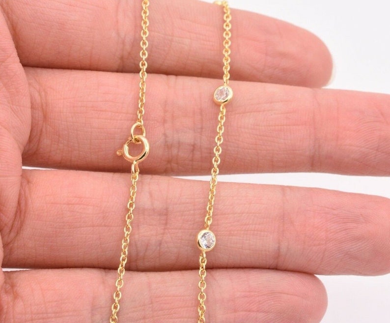 May include: A gold chain necklace with two small clear stones.