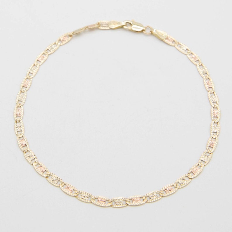 Puede incluir: Un brazalete de cadena de oro con un dise&ntilde;o delicado y estampado. La cadena est&aacute; hecha de oro de dos tonos, con una mezcla de oro amarillo y oro rosa.