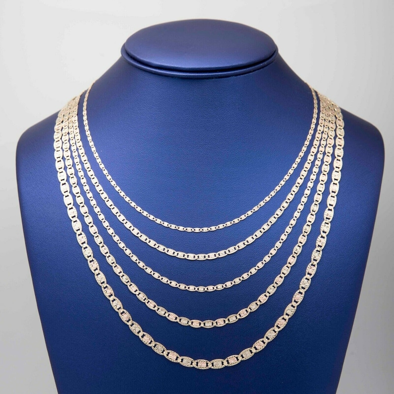 May include: A set of five silver chains of varying lengths, displayed on a blue velvet stand. The chains are all made of a mariner link pattern.
