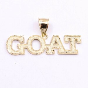 May include: Gold pendant necklace with the word "GOAT" in a diamond-cut style.